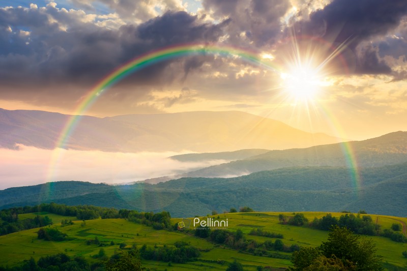 sunset over foggy carpathian countryside scenery in summer. view sunset over foggy carpathian countryside scenery in summer. view of mountainous landscape with rural fields on rolling hills. fog in the valley. clouds above the mountain. weather with rainbow