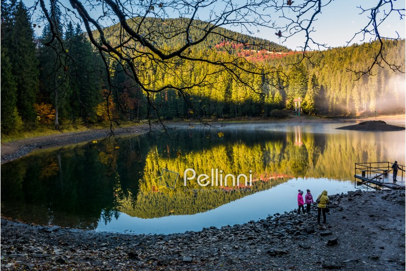 National Park Synevyr, Ukraine - October 23, 2016: tourists on Synevyr lake in autumn. high altitude mountain lake among spruce forest. The most visited place in Carpathians on beautiful foggy morning
