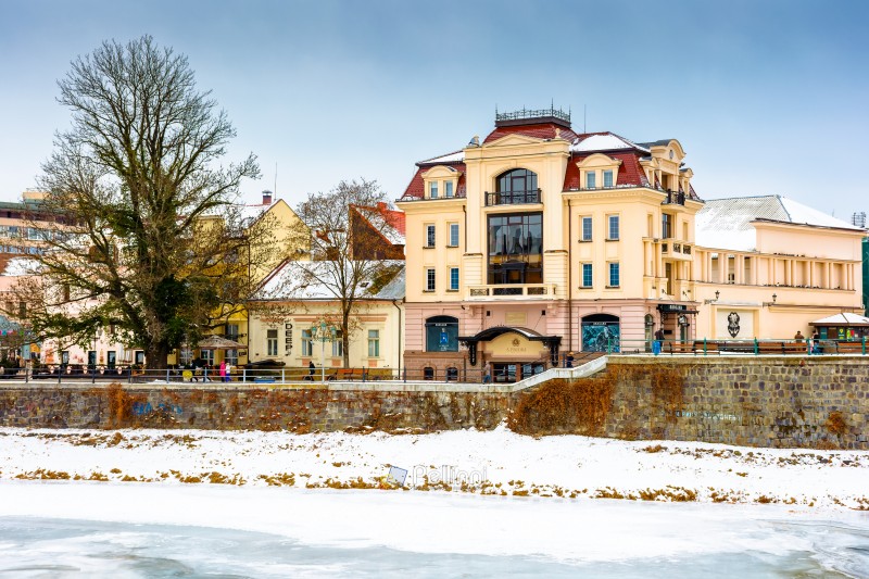 uzhhorod, ukraine - 09 jan 2017: christmas time in the old town in winter. snow covered embankment of ice frozen river uzh. cold weather. timeless photo of transcarpathia capital on holiday season