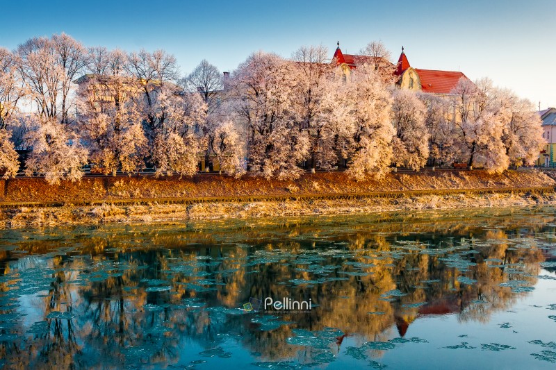 uzhhorod, ukraine - 10 jan 2010: uzh river in the old city in wi uzhhorod, ukraine - 10 jan 2010: uzh river in the old city in winter. cityscape with hoarfrost on the embankment. european urban landscape with school building reflecting in the water with ice