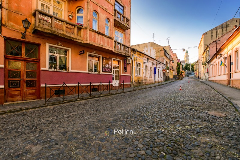 uzhhorod, ukraine - 11 jun, 2017: narrow street of old town leads to square in empty historic center at sunrise. beautiful architecture of uzhhorod in morning light under blue sky. scenic downtown