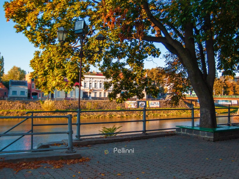 uzhhorod, ukraine - 30 aug, 2007: Uzh river in morning light. cityscape of the old european town reflecting in the water. grass embankment with trees and old architecture