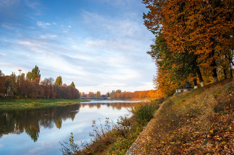 uzhhorod, ukraine - 31 oct, 2009: embankment of the river Uzh in autumn. beautiful urban scenery with colorful foliage on trees in morning light. scenic european downtown in fall season