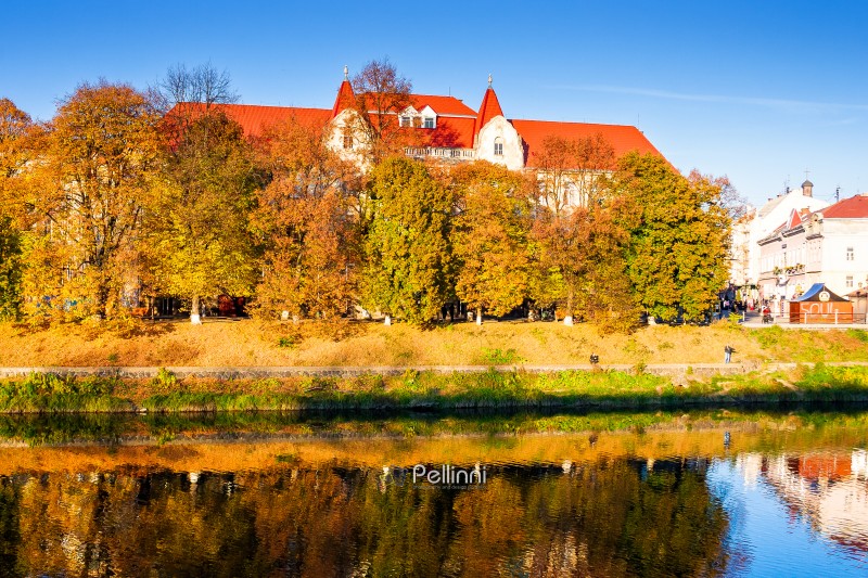 uzhhorod, ukraine - 31 oct, 2010: embankment of the river Uzh in autumn. beautiful view of old city with colorful foliage on trees in evening light. scenic european downtown in fall season
