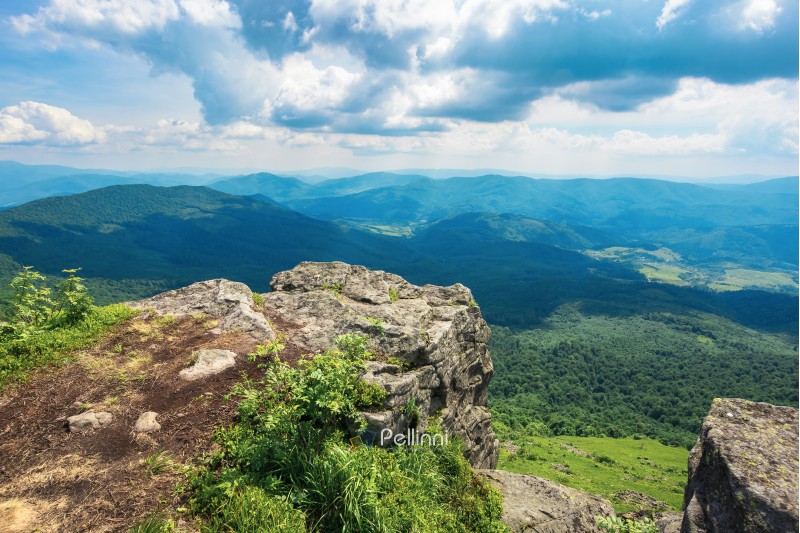 view from a rocky cliff in to the distant valley. beautiful summer landscape in mountains. huge ridge in the distance. view from above. cloudy weather