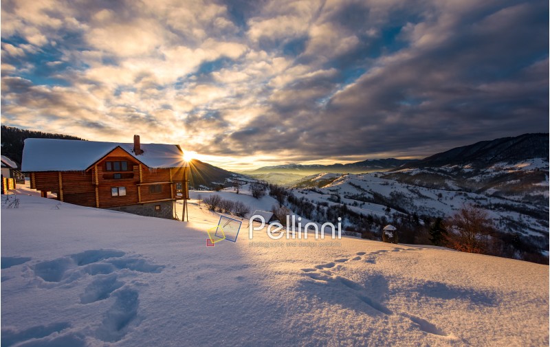 wooden chalet in village outskirts at sunrise. gorgeous landscape in winter Carpathian mountains, great place for vacation