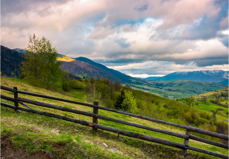 wooden fence across the hill. beautiful agriculture scenery of Carpathian mountains on a cloudy springtime day