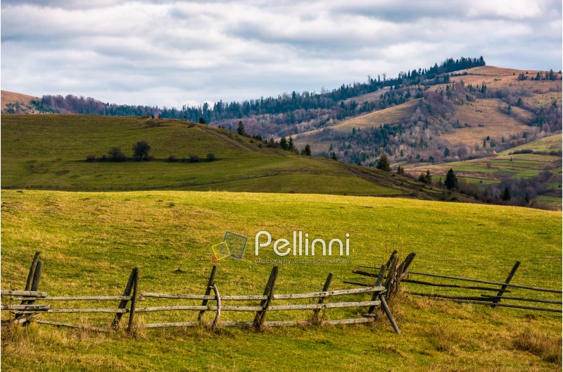 wooden fence on grassy rural hill in late autumn sunny day. beautiful scenery in mountainous area