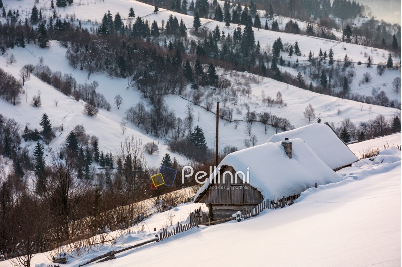 woodshed on hillside in deep snow. beautiful winter rural scenery in the mountainous village outskirts at sunrise