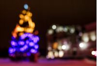 Abstract Christmas lights background at night. Christmas tree on the city square blurred with bokeh effect 