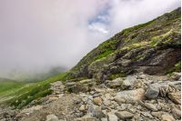 edge of steep slope on rocky hillside in foggy weather. dramatic scenery in mountains