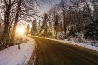 asphalt road through winter forest at sunset. beautiful transportation scenery