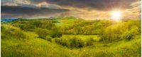 beautiful countryside panorama in springtime at sunset. grassy hills and meadows. trees with green foliage on hillsides. mountain top in the distance. wonderful nature scenery of Carpathians