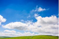 deep blue sky with some clouds over the green and grassy hills of Carpathian alps. road winds uphill the hillside meadow. beautifull minimalistic summer landscape in good day weather.