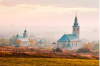 catholic and orthodox churches at foggy sunrise. lovely countryside scenery in autumn. creative toning