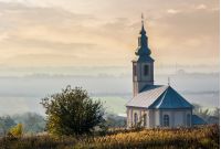 church on a hill over the hazy rural valley at sunset. lovely autumn countryside scenery