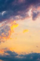 dark cloudscape at sunset. orange-purple clouds on a yellow-blue gradient of sky in evening light. dramatic weather change. wind forecast background. place for copy space. narrow telephoto shot
