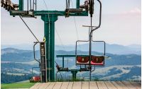 empty ski elevator with red chairs on top of a hill Gymba. Carpathian mountain ridge Borzhava, Ukraine. Lovely mountain landscape with clear sky