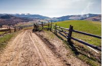 fence along the country road in rural area. lovely agricultural landscape in Carpathian mountains. grassy fields on hill in springtime. Location Volovets, Ukraine