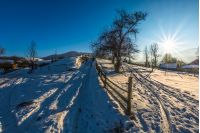 fence on the snow covered rural field on mountain slope near the village in winter day