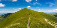 footpath through grassy peak of mountain ridge. gorgeous panorama of summer landscape with fine weather and blue sky with some clouds. hiking destination concept