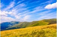 summer landscape in mountains. green grassy meadows on top of the ridge. blue sky with white clouds