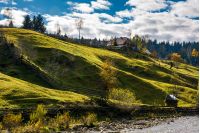 grassy rural hillside near the village in autumn. beautiful countryside scenery