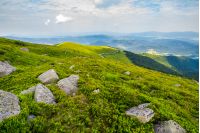 grassy slope with huge rocks. wonderful summer landscape in mountains. winding path through the distant hill. cloudy forenoon