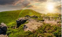 huge boulders on the edge of hillside at sunset. fine weather in summer mountain landscape with rainbow