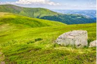 mountain summer landscape. meadow with huge stone among the grass on top