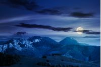 landscape in mountains with rocky formations. grassy meadows, forested hills and huge cliffs. wonderful nature scenery. beautiful weather at night in full moon light in springtime