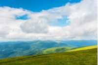 landscape in mountains. hills and meadows. sunny weather with beautiful cloudscape. grassy green slope and distant ridge.