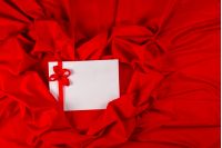 love card. white card with a red ribbon on a red fabric