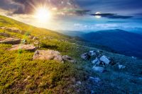mountain landscape with grass and rock on a slope. day meet night. view in to the distant valley of carpathian mountains. sun and moon in harmony over mountainous scenery of ukraine on summer solstice
