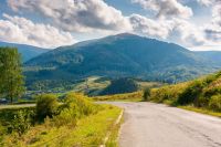 mountain pass on a sunny evening. road winding down the hill. scenery with valley of volovets in front of temnatyk peak under cloudy sky
