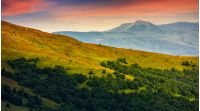 mountain ridge with peak behind the hillside. beautiful summer background at sunset with red sky;