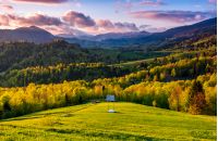 mountain rural area in springtime. agricultural fields on hills with forest. beautiful and vivid countryside landscape with cloudy sky at sunset.