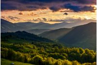 mountain rural area. agricultural fields on hills with forest. beautiful and vivid countryside landscape with cloudy sky at sunset.