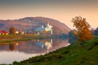 mukachevo, ukraine - 06 nov, 2015: urban landscape with river and trees in autumn. reflection of a monastery in the distance. beautiful travel destination of transcarpathia