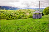 old wooden hay shed on grassy hillside. beautiful scenery of mountainous rural area in springtime