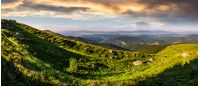 panorama of mountain ridge with peak behind the hillside. beautiful summer background at sunset with cloudy sky