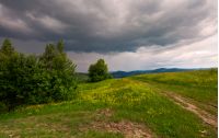 path across the grassy hill. lovely summer scenery. hiking and outdoor activities concept. dark cloudy sky.