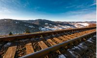 railroad in mountains with snowy slopes. lovely transportation scenery on winter sunny day