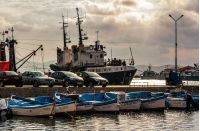 SOZOPOL, Bulgaria - AUGUST 19, 2015: rain in port of Sozopol at sunset. small fishing boats and few big one docked near pier with cars.