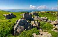 range of stones on the grassy hill. beautiful summer landscape with fluffy clouds above the distant mountain ridge