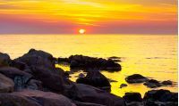 reddish sunrise over the sea with rocky shore. beautiful summer scenery and vacation concept