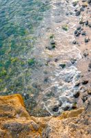 rock texture at the sea. ocean coast background. transparent water. calm wave and seaweed