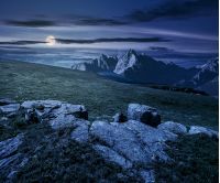 Composite night landscape with full moon. rocky peaks of mountain ridge and rocks on hillside under the dark sky with clouds and stars. picturesque fantasy view.