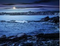 SOZOPOL, BULGARIA - SEPTEMBER 11, 2013: rocky shore and sandy city beach in mellow season. Beautiful and warm weather on the coast of Black sea at night in full moon light