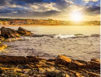 SOZOPOL, BULGARIA - SEPTEMBER 11, 2013: rocky shore and sandy city beach in mellow season. Beautiful and warm weather on the coast of Black sea at sunset.